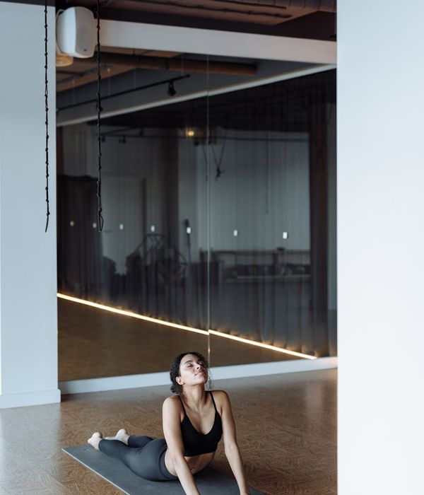 Woman in a calm yoga pose in a dark, minimalist studio.